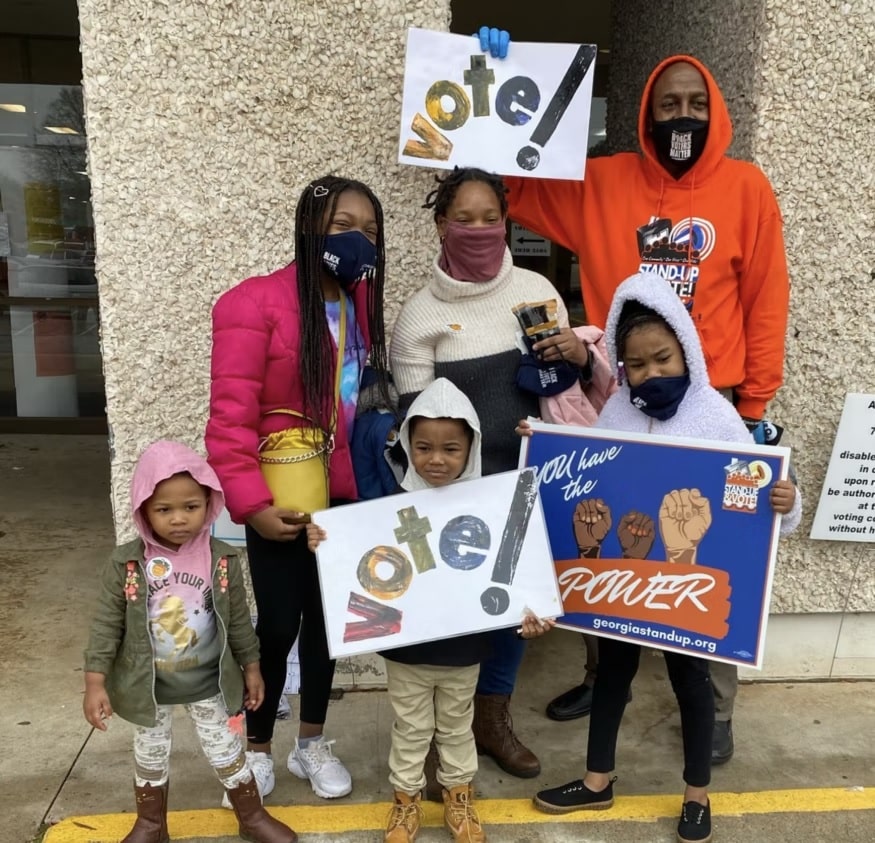Family standing outside with Vote! signs
